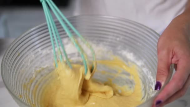 Closeup view of female hands preparing dough mixing ingredients using whisk in the kitchen. Homemade food. Slowmotion shot - Záběry, video