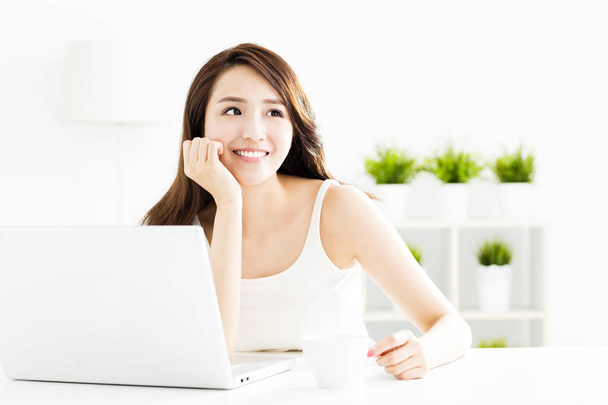 smiling young  woman with laptop in living room - Фото, изображение