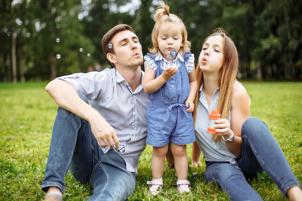 Family blowing bubbles in the park - Foto, afbeelding