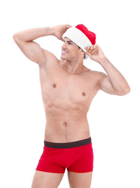 Muscle man in Christmas hat on white background - Fotoğraf, Görsel