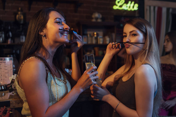Novias teniendo una fiesta sosteniendo copas de cócteles, divirtiéndose, haciendo bigote con paja en el club nocturno
 - Foto, imagen