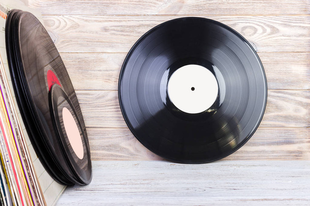 Retro style image of a collection of old vinyl record lp 's with sleeves on a wooden background. Копирование пространства
. - Фото, изображение