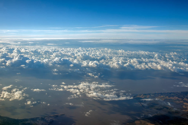 Ciel bleu, nuages et terre visibles à travers eux depuis une fenêtre plane
. - Photo, image