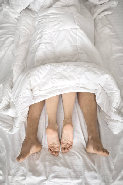 Legs of lovers under blanket - Фото, изображение