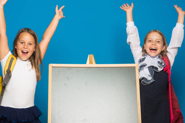 Schoolgirls with happy faces stand near blackboard - Fotoğraf, Görsel