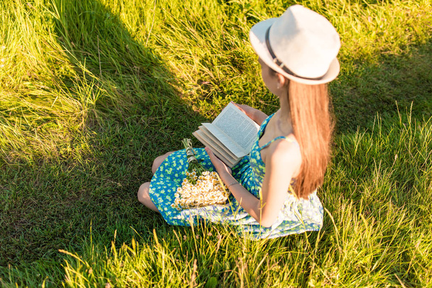 Молодая романтичная девушка читает книгу сидя на траве
 - Фото, изображение