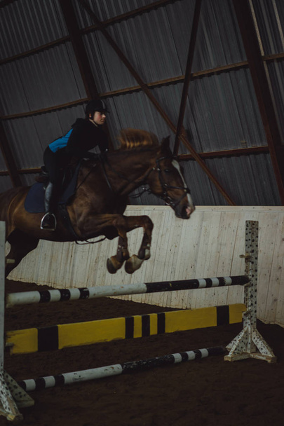 girl jumping on horse through obstacle - Фото, изображение