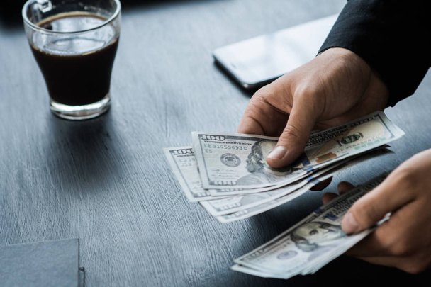 O jovem empresário branco conta o dinheiro, notas de cem dólares num plano de fundo negro, Motion blur. Conceitos de negócios e finanças. vista superior $100
 - Foto, Imagem