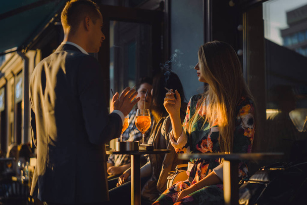 Man and woman drinking cocktails in street cafe - 写真・画像