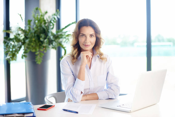  businesswoman sitting at desk - Фото, изображение