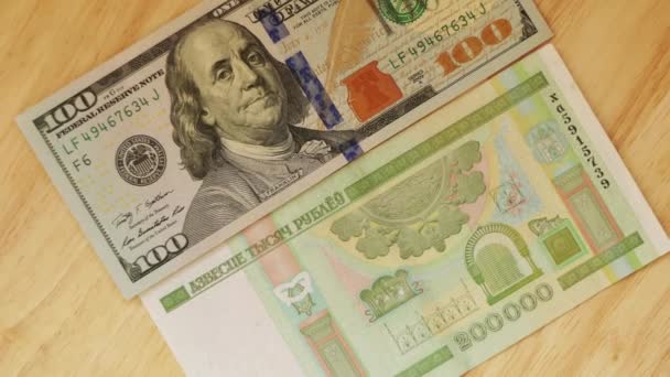 Белорусские рубли номинальной стоимостью двести тысяч лживых и доллар США на деревянном столе
. - Кадры, видео