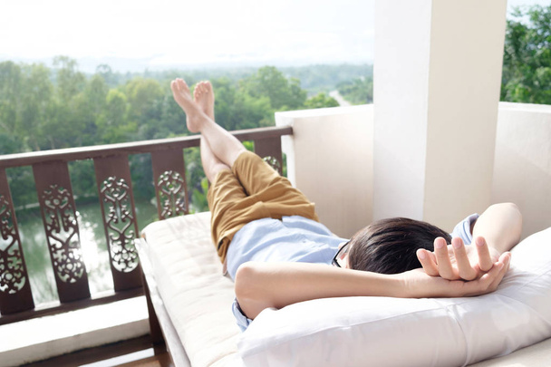 Hombre relajándose en su silla y disfrutando de la vista desde la terraza
. - Foto, Imagen