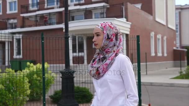 Mujer árabe joven caminando por la calle con un hijab en una ciudad moderna
 - Imágenes, Vídeo