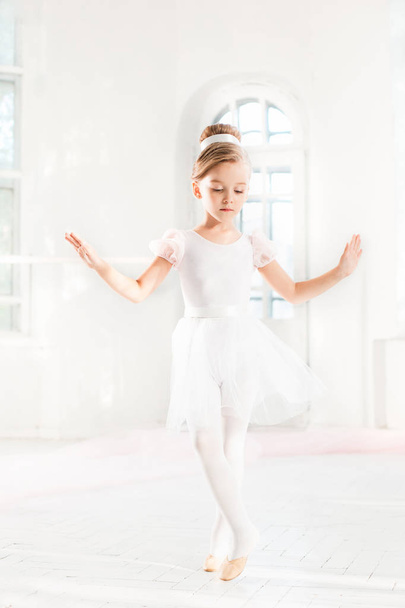 Little ballerina girl in a tutu. Adorable child dancing classical ballet in a white studio. - Foto, Imagen