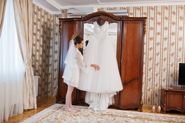 Portrait of a beautiful bride posing with her dress on a hanger  - Фото, зображення