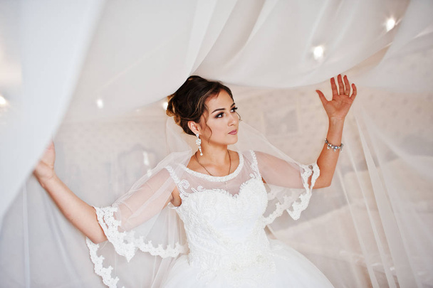 Portrait of a stunning bride posing with curtains in her room on - Foto, imagen
