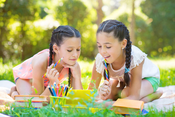 Happy hispanic girls drawing and studying in park - Photo, image