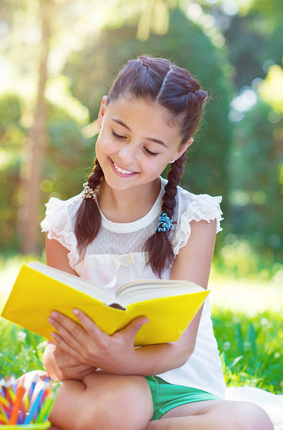 Portret van mooie jonge meisje leesboek in park - Foto, afbeelding