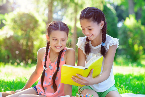 Happy hispanic girls drawing and studying in park - 写真・画像
