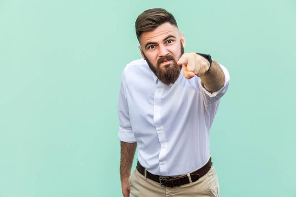 Angry bearded businessman with white shirt looking at camera and pointing finger to you. Studio shot isolated on light green background. - Fotografie, Obrázek
