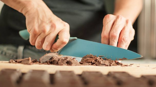 Woman hands chopping chocolate block for celebratory cake - Photo, image