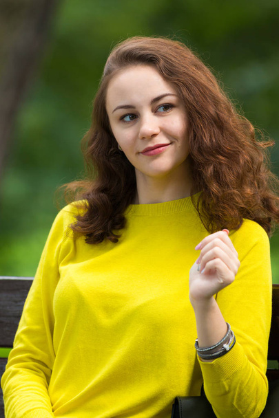 Portrait of the beautiful fashionable girl on bench in park - Фото, зображення