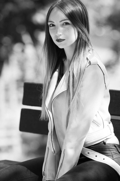 Retrato de chica informal de moda en el banco en el parque, colores blanco y negro
 - Foto, Imagen