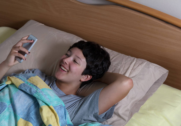 Teen ragazza ridendo mentre controllava il suo messaggio sul dispositivo mobile d
 - Foto, immagini