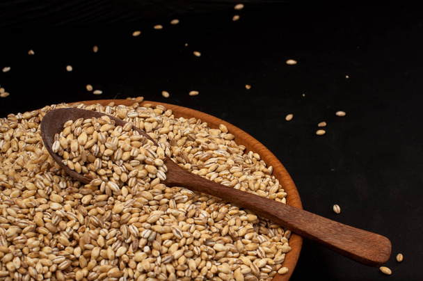 Grano entero de cebada perlada o derrame de trigo sobre fondo negro derecho. Agricultura alimentos semillas crudas
. - Foto, imagen