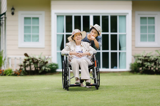 Seniorin sitzt mit Tochter im Rollstuhl im Hinterhof - Foto, Bild