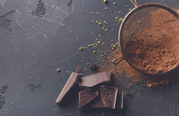 Polvo de cacao en un tamiz sobre fondo de pizarra negro
 - Foto, imagen