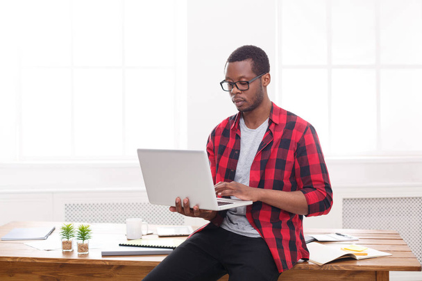 Homme d'affaires noir pensif dans un bureau décontracté, travailler avec un ordinateur portable
 - Photo, image