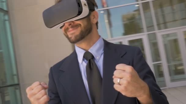 Man in suit wearing VR goggles celebrating victory while camera circles him - Filmagem, Vídeo