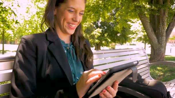 Happy smiling businesswoman working on digital tablet technology in park - Séquence, vidéo