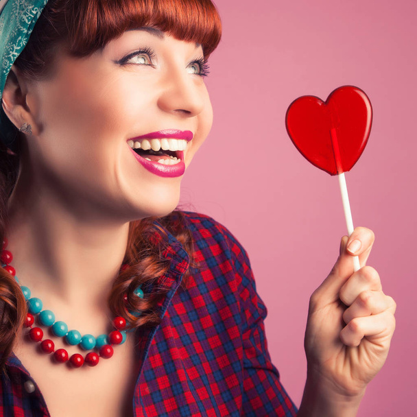  girl posing with red heart-shaped lollipop  - Foto, afbeelding