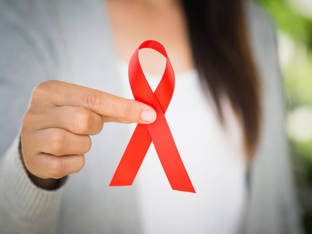 Closeup mão mulher segurando fita vermelha HIV, dia mundial da AIDS
  - Foto, Imagem