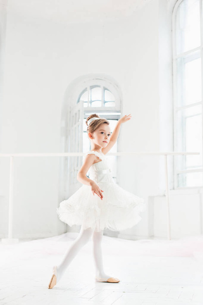 Little ballerina girl in a tutu. Adorable child dancing classical ballet in a white studio. - Foto, Imagem