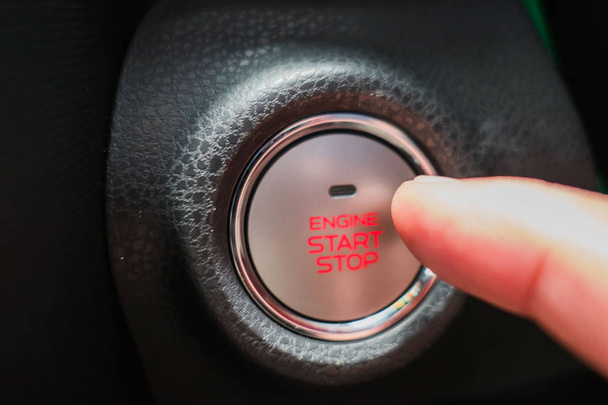Bliska przycisk start/stop silnika i palec naciskający na samochód  - Zdjęcie, obraz