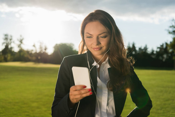 businesswoman in earphones with smartphone - 写真・画像