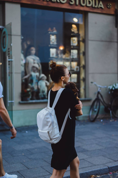 バックパックと手で犬と一緒に歩いている女性 - 写真・画像