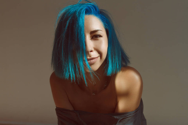 Pozitivní portrét dívky s modrými vlasy na slunci na zeď pozadí - Fotografie, Obrázek