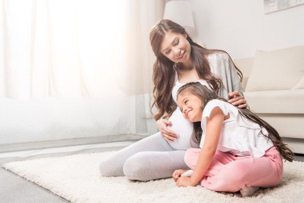 Femme enceinte avec fille écoutant le ventre
 - Photo, image