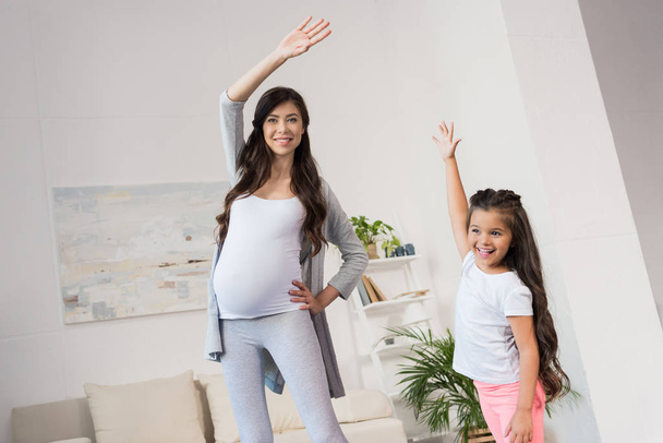 Pregnant woman and daughter exercising - Fotó, kép