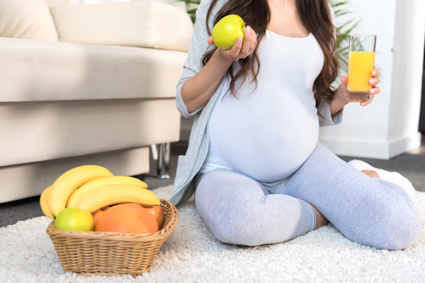 Mujer embarazada sosteniendo manzana y jugo
 - Foto, imagen