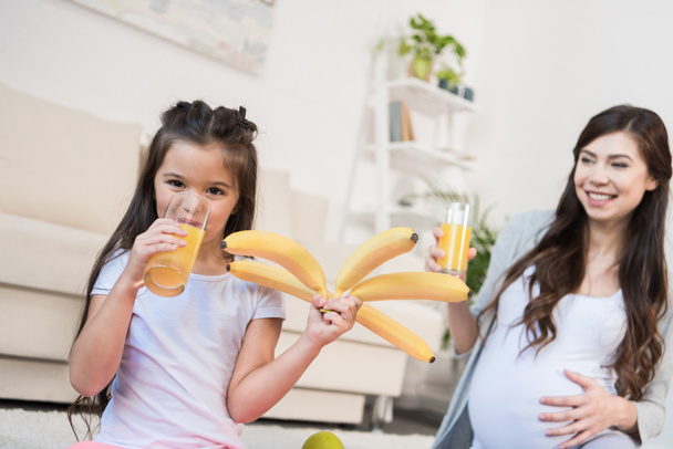 Mädchen hält Bananen und trinkt Saft - Foto, Bild