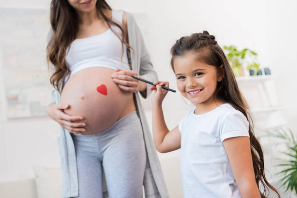 Mädchen zeichnet auf schwangerem Bauch der Mutter - Foto, Bild