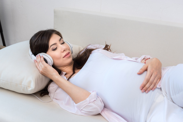 Mujer embarazada con auriculares grandes
 - Foto, imagen
