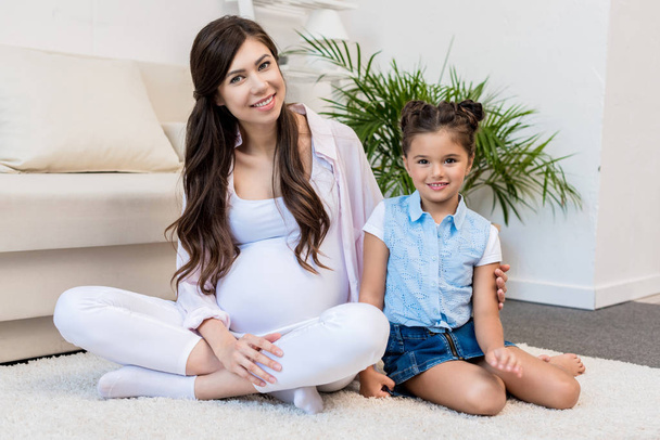 A szőnyegre ül lánya terhes nő  - Fotó, kép