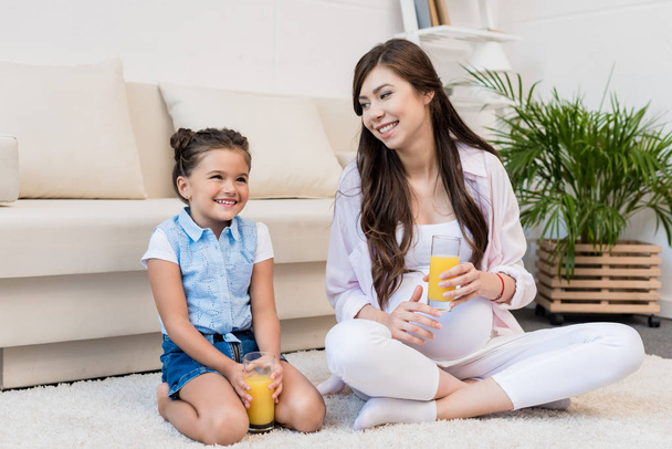 Pregnant woman and daughter with glasses of juice - Foto, Bild