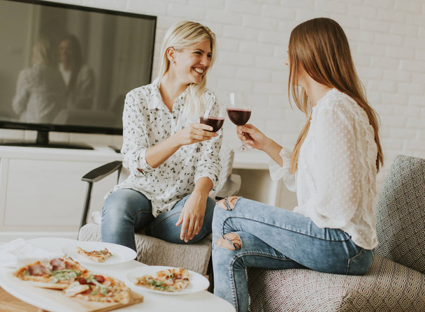 かなりのピザを食べる若い女性と赤ワインを飲む - 写真・画像